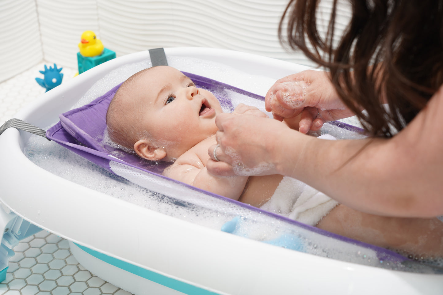 Purple baby bath hammock attached to a safety bathtub, designed for newborn comfort and support in the bath tub.