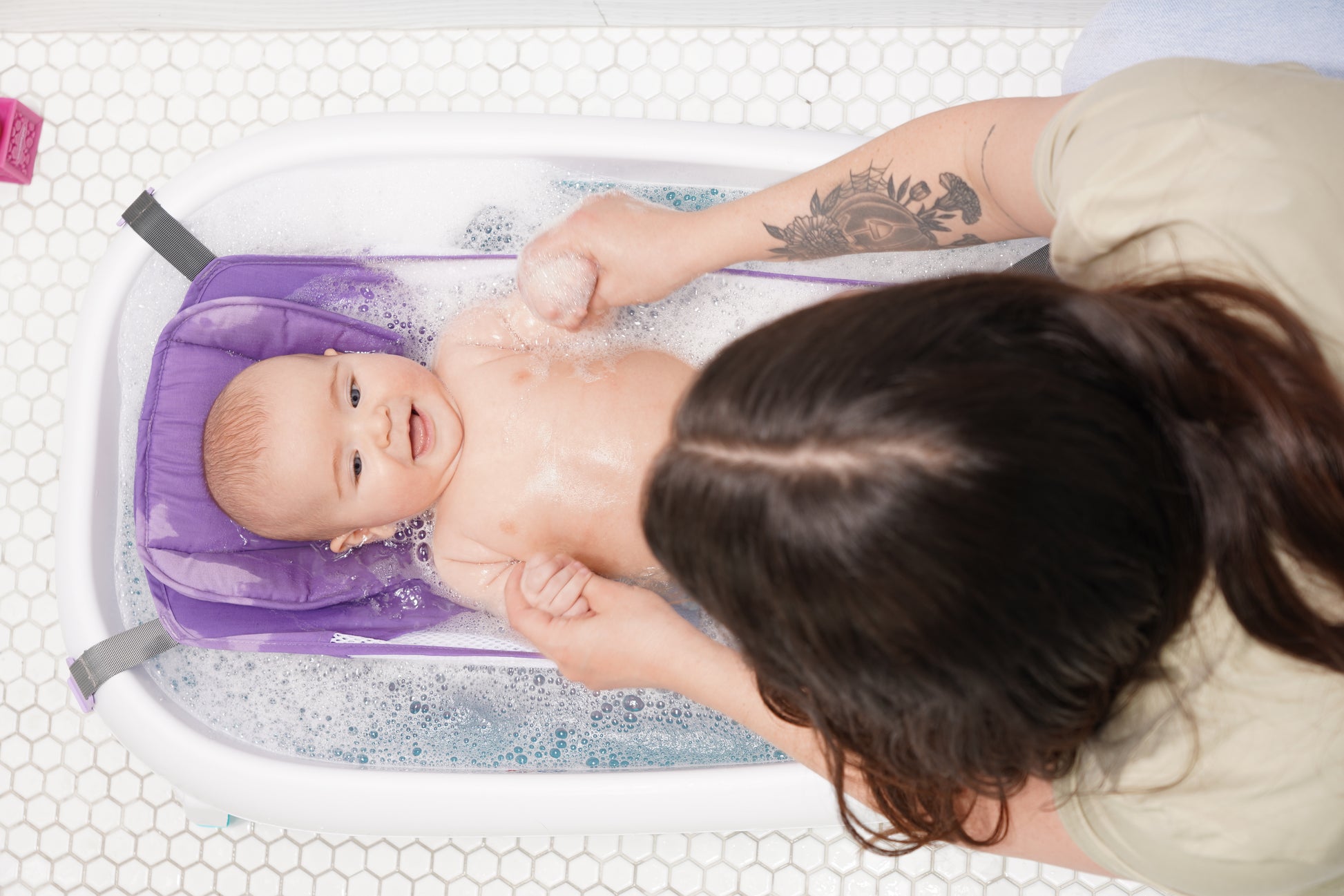 Purple baby bath hammock attached to a safety bathtub, designed for newborn comfort and support in the bath tub.