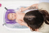 Purple baby bath hammock attached to a safety bathtub, designed for newborn comfort and support in the bath tub.